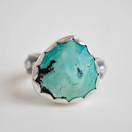 Turquoise ring with silver band on a light gray background