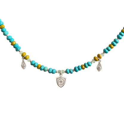 Faceted turquoise and vintage green Czech glass beads with a sterling silver shield pendant and small sterling silver daggers. This one-of-a-kind necklace is 18" long.